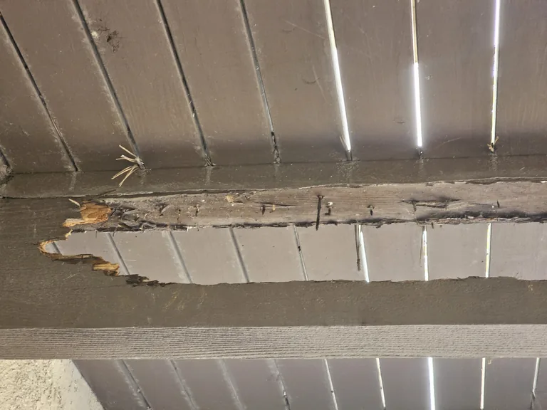Deck beam before repair, showing exposed deteriorated wood and missing material